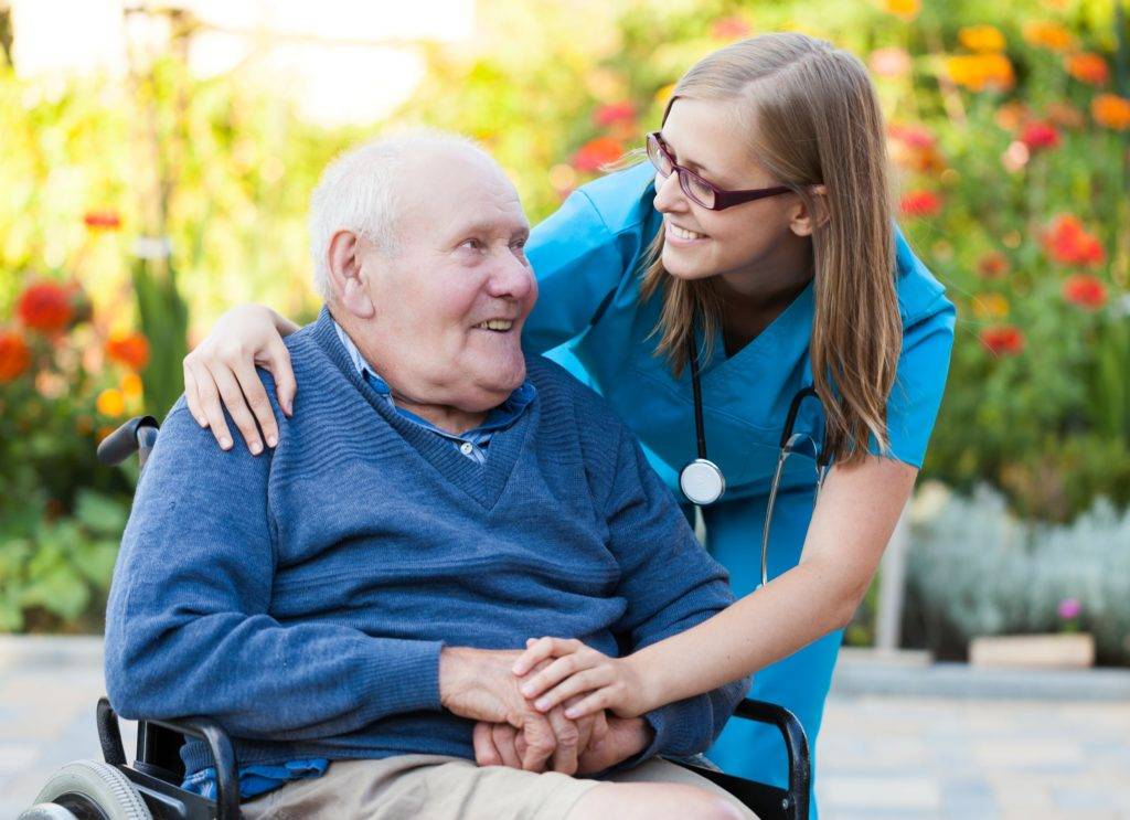 smiling nurse hugging disabled senior man